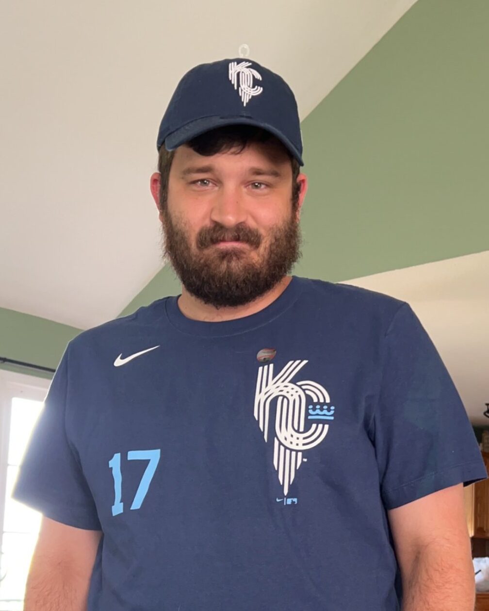 Young white man with a Kansas City Royals hat and blue Kansas City Royals shit on with the number 17 and the nike swoosh